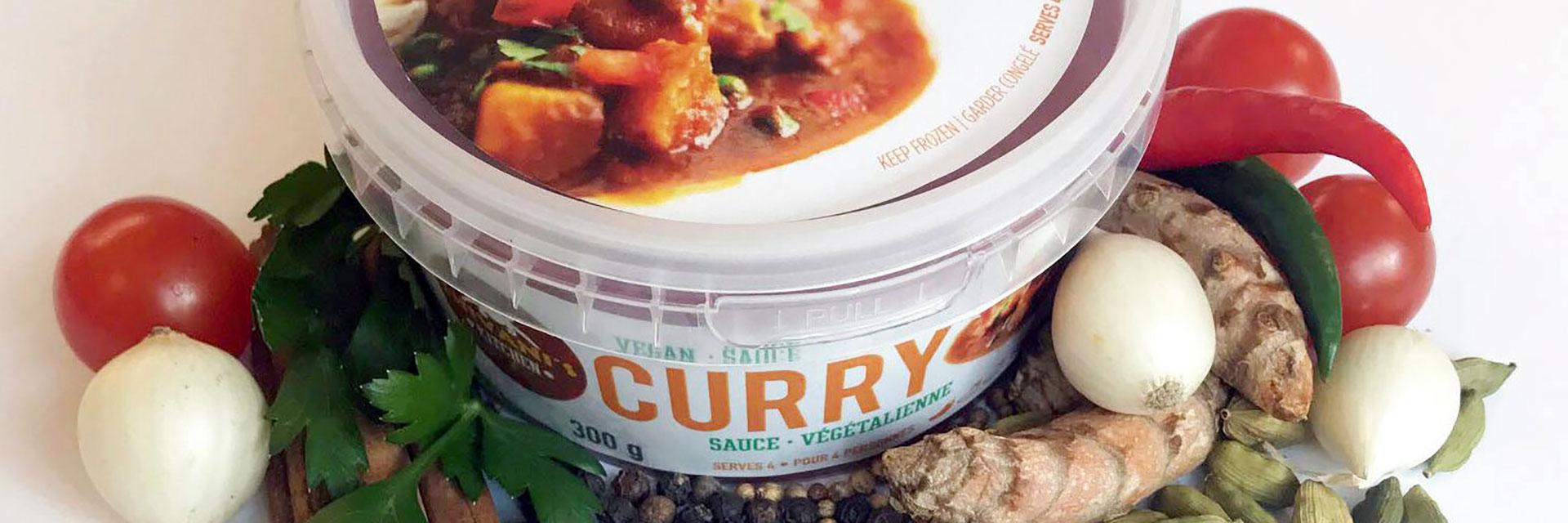 A container of Shivani's Kitchen curry surrounded by ingredients.